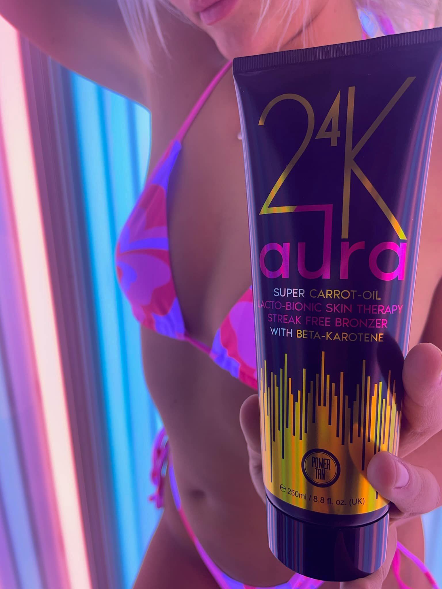 A tube of 24K Aura tanning lotion held in a sunbed
